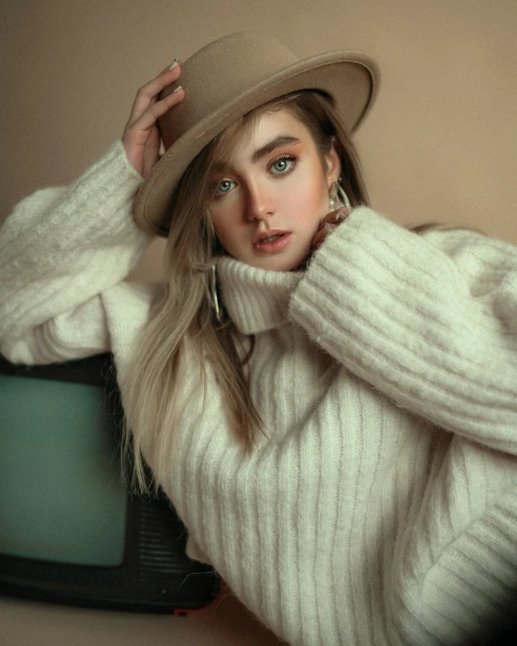 a woman wearing white in an oversized sweater and hat