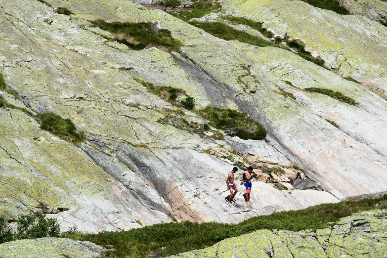 two people walking up a steep hill on the rocks