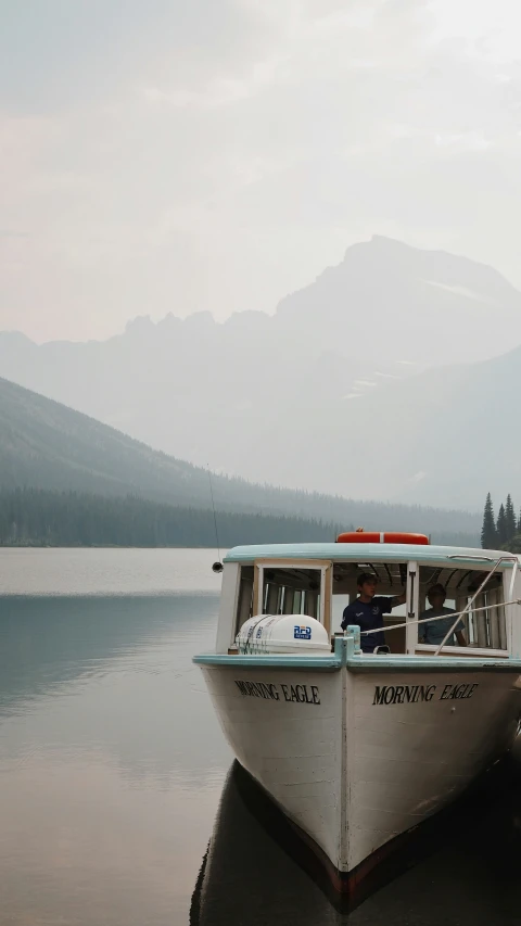 a small boat sailing on a lake surrounded by mountains