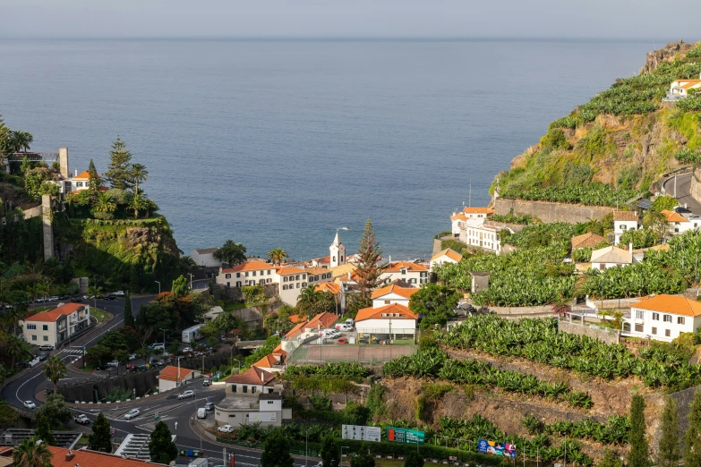 the small town on the side of the mountain with an ocean behind it