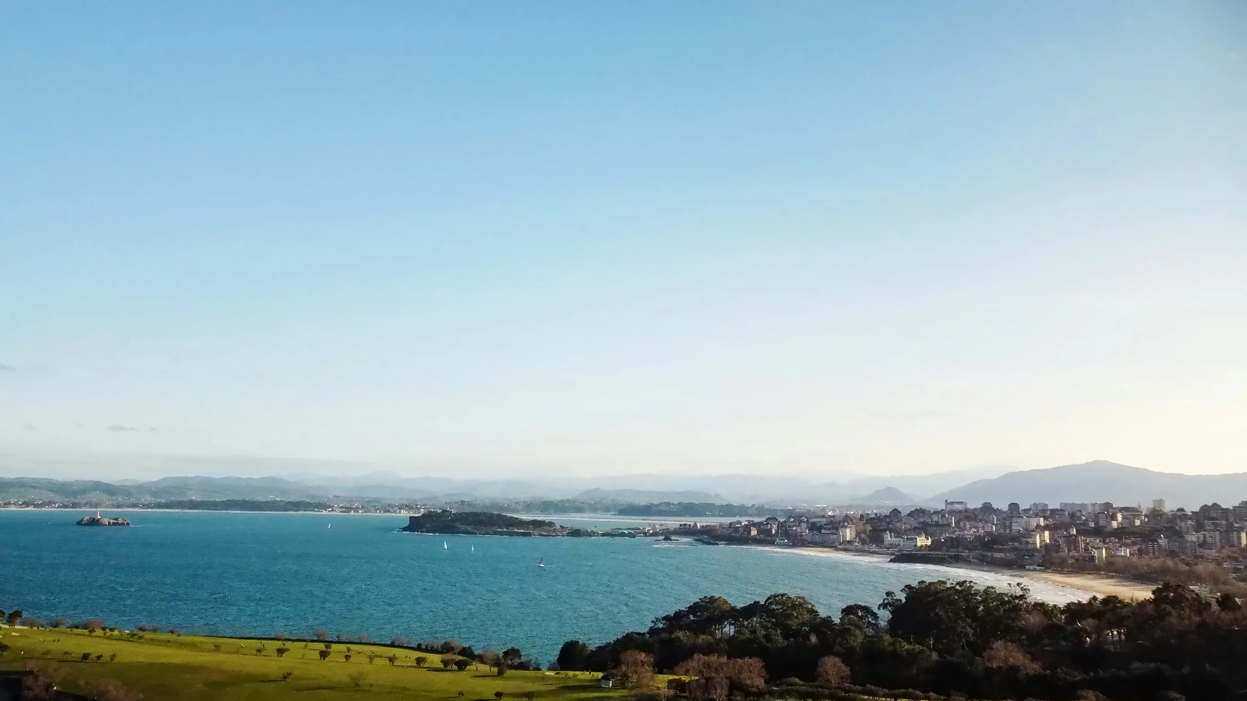 the ocean is seen from above a hill with boats on it