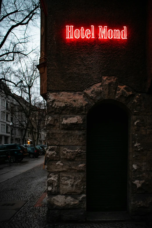 a red neon sign in the middle of a dark street