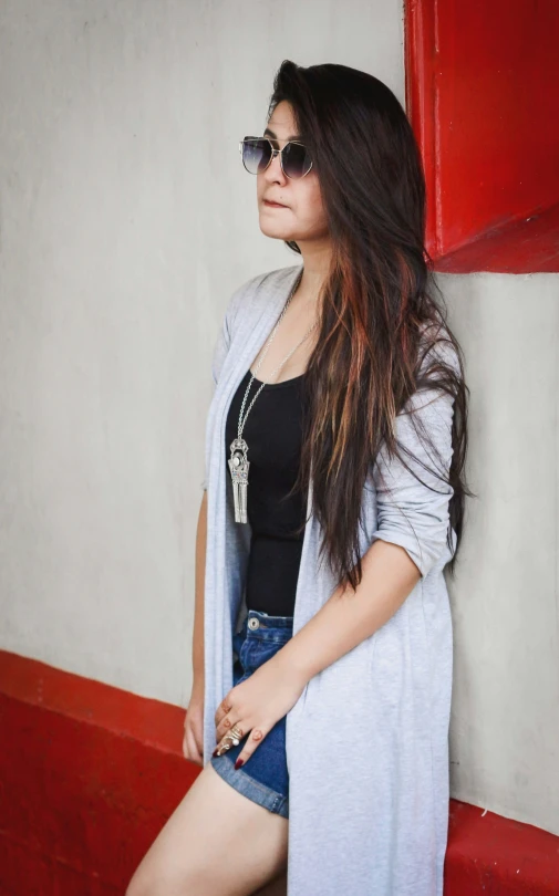 a beautiful young lady posing against a wall