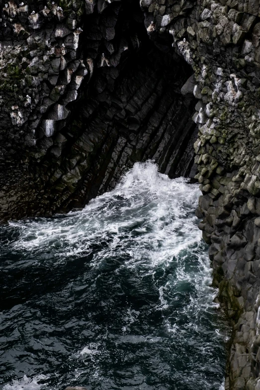 a dark cave with white water is coming up out of the hole