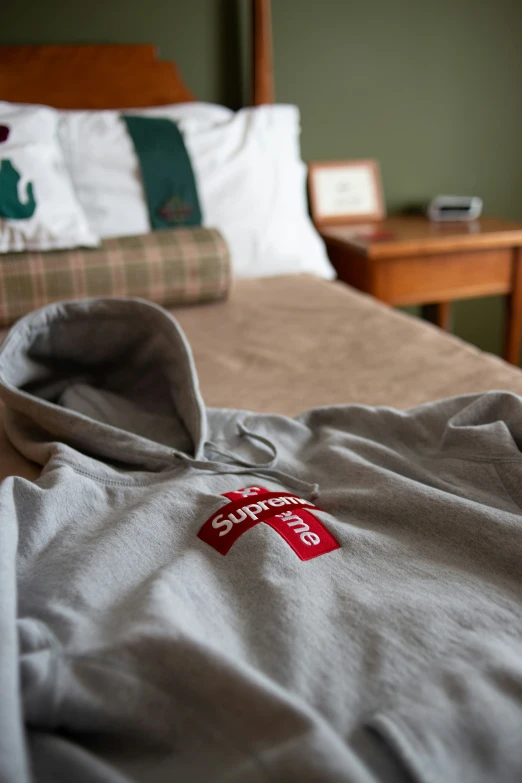 a bed with an unmade, grey blanket and brown chair