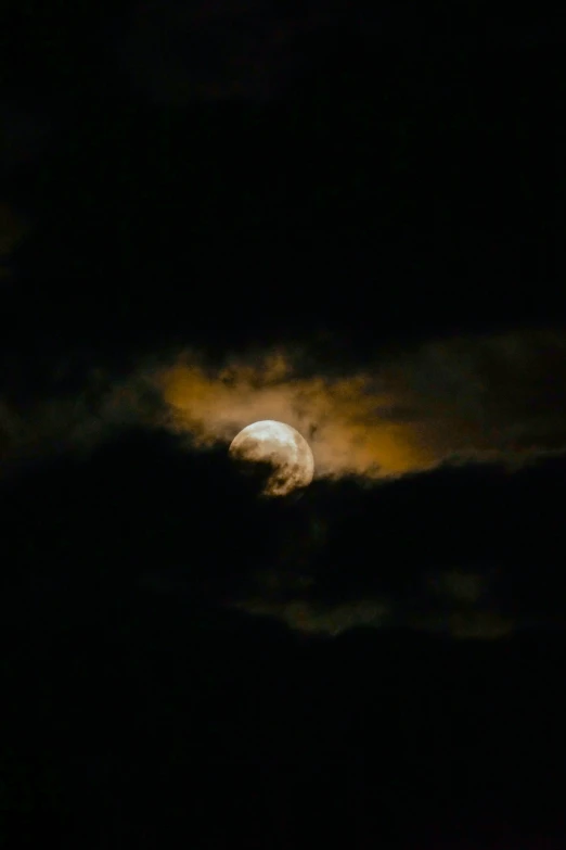 a full moon rising through the dark clouds