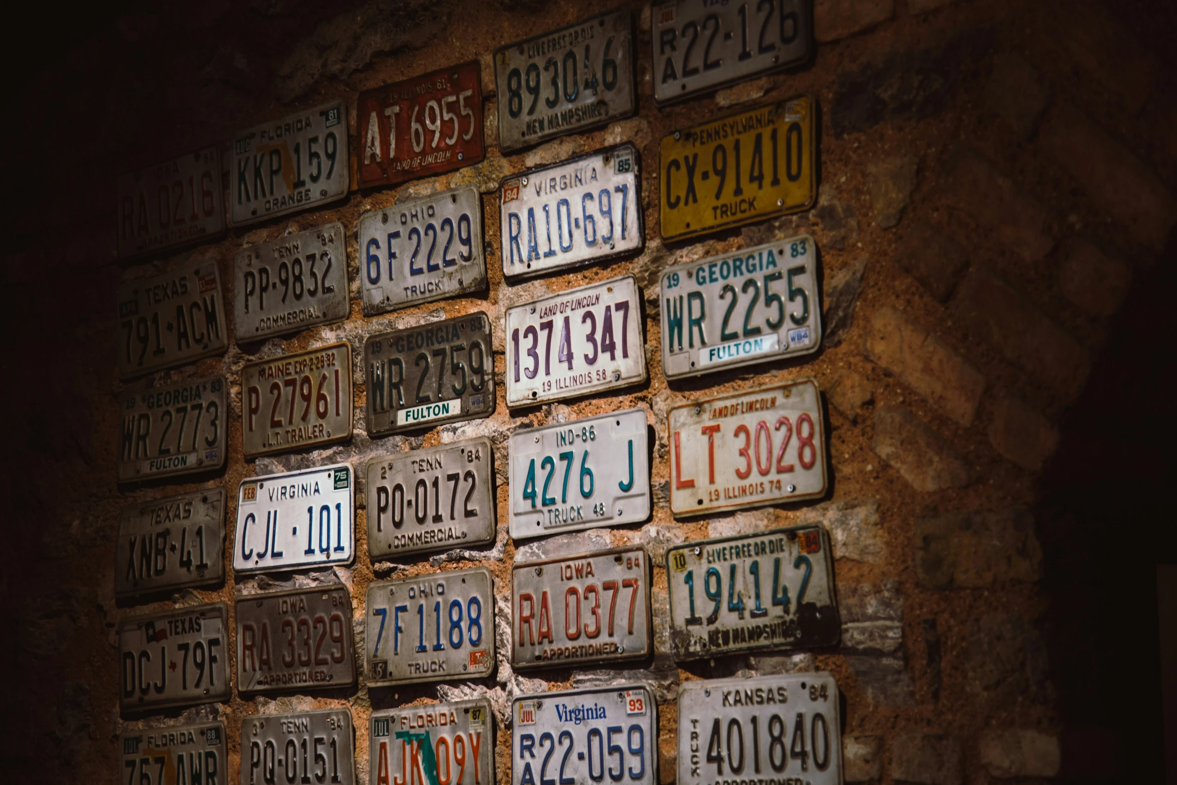 a group of license plates on display in a stone wall