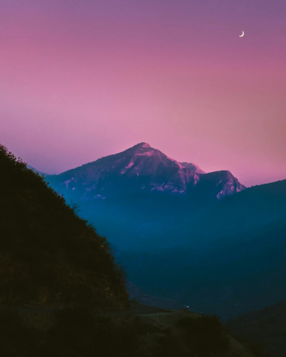 the sky above the mountain has a pink and blue hue