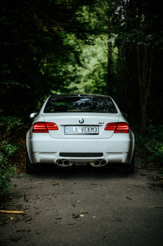 a white car parked in the middle of a wooded road