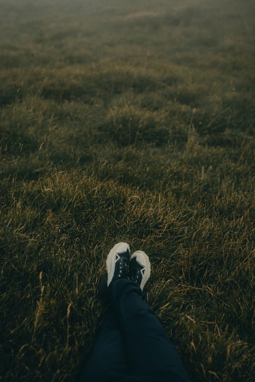 someone is laying in the grass on a gloomy day