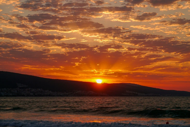 the sun sets over a mountain on the horizon