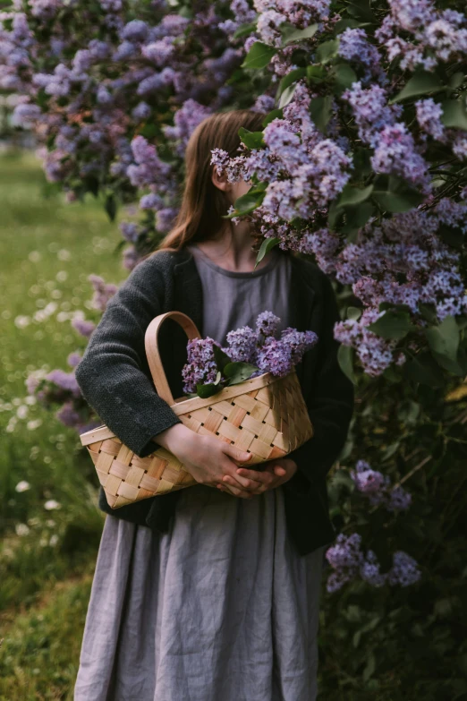 a woman holding a basket full of purple flowers