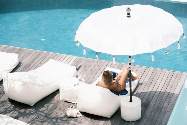 woman sitting on a bean bag next to the pool with an umbrella