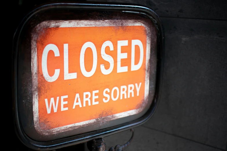 a closed sign posted against a dark concrete wall