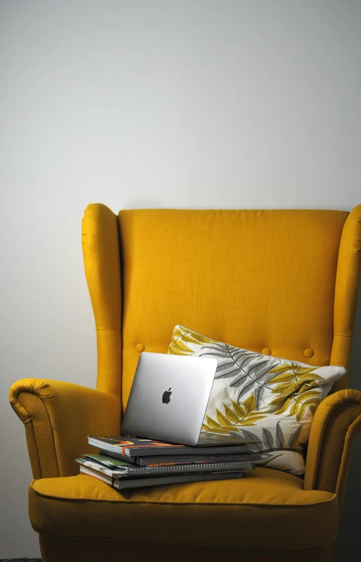 a yellow chair with a laptop sitting on top of it