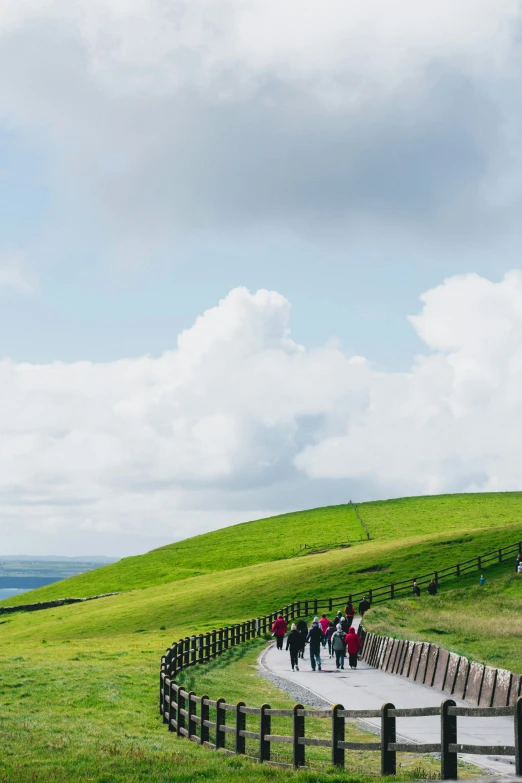 a group of people walking down a long trail near the ocean