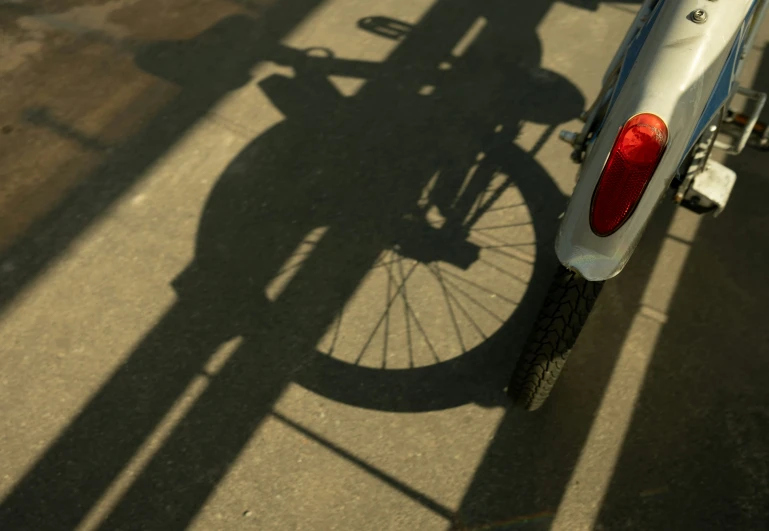 an old motorcycle with its shadow cast on the ground