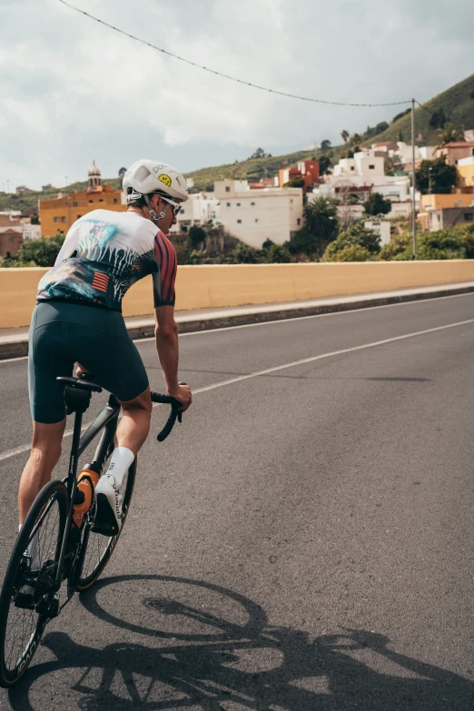 man riding bicycle on roadway near buildings and water