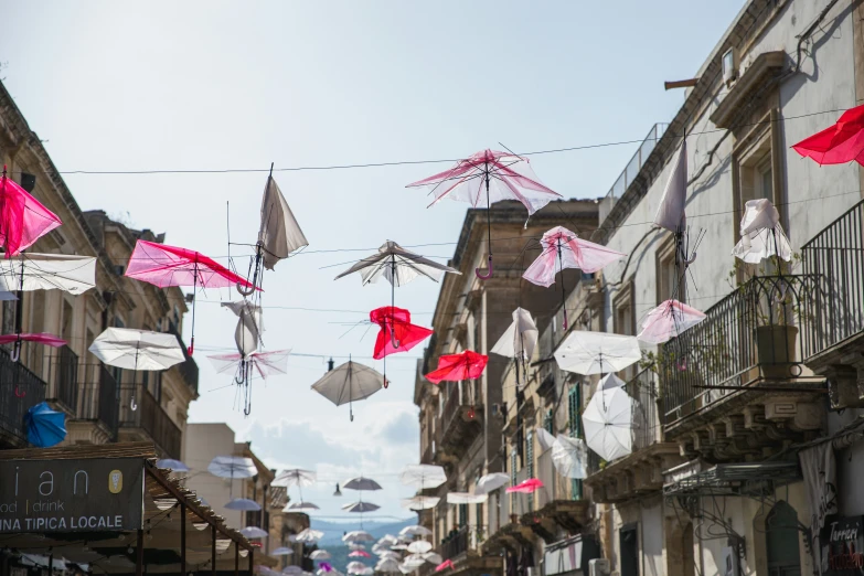 some umbrellas are hanging from the wire on the buildings