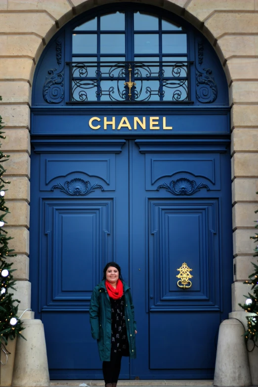 a lady is standing outside of a blue door