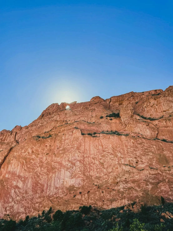 the sun shining over a mountain with a rocky cliff