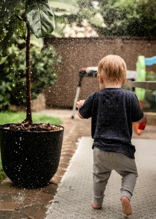 a little boy throwing water off of a sprinkle