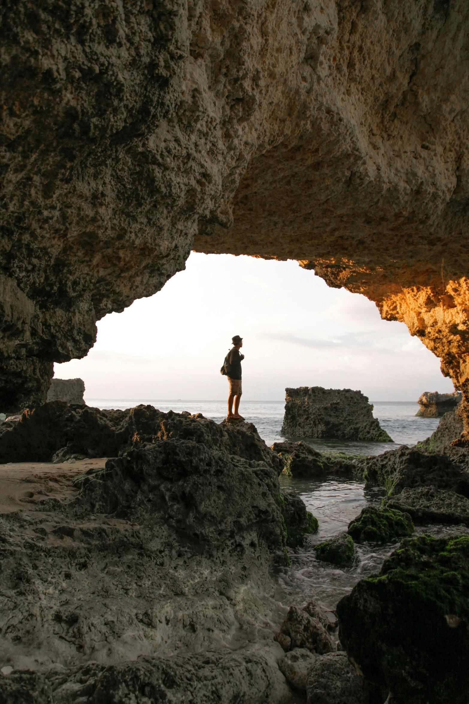 a person standing at the end of a cave on the beach