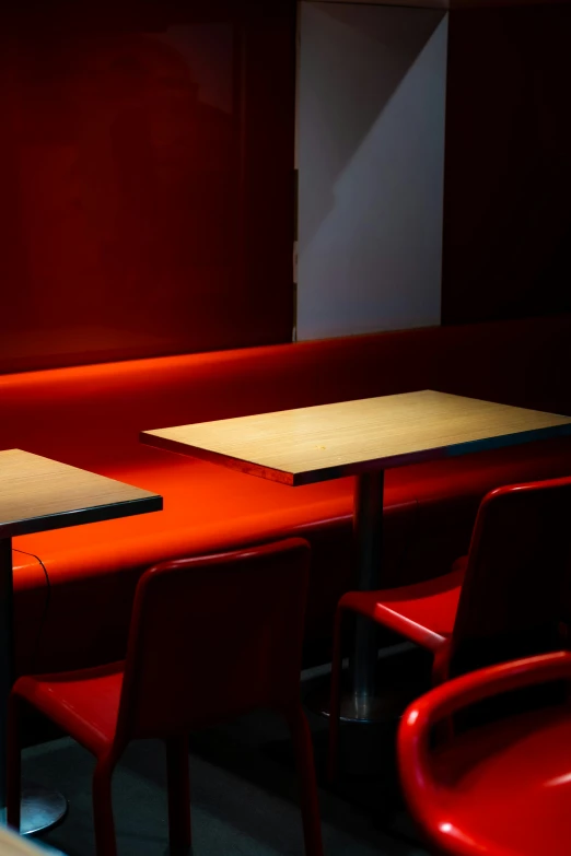 an empty room with tables and red chairs