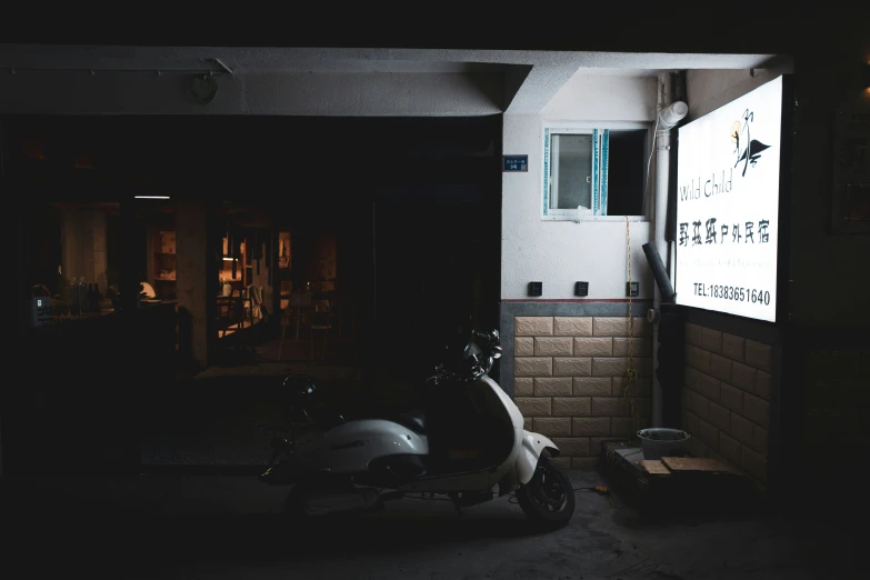 a scooter is parked outside of a bar in a dark area