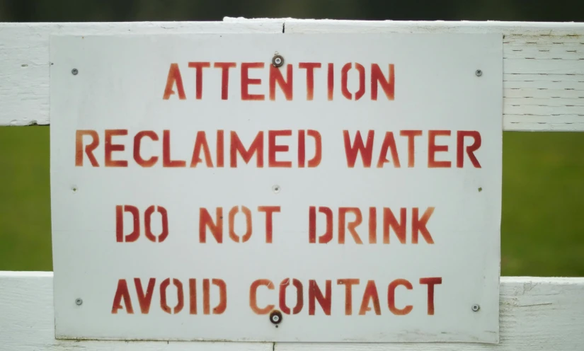 there is an orange red and black sign that is posted on the white fence