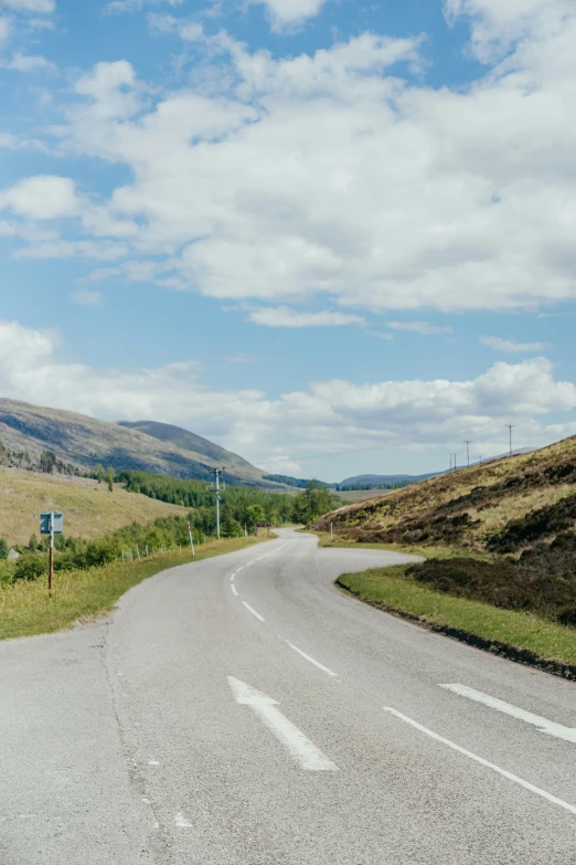 an empty country road leading toward the mountains