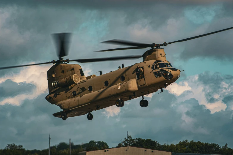 a black military helicopter flying under a cloudy sky