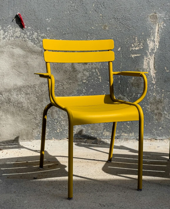 yellow chair on the sidewalk against an old stone wall