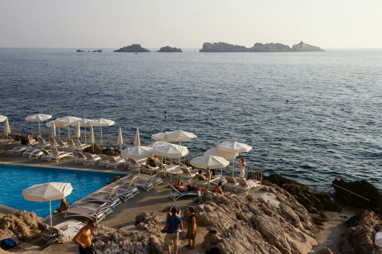 many white umbrellas by a pool with people at it