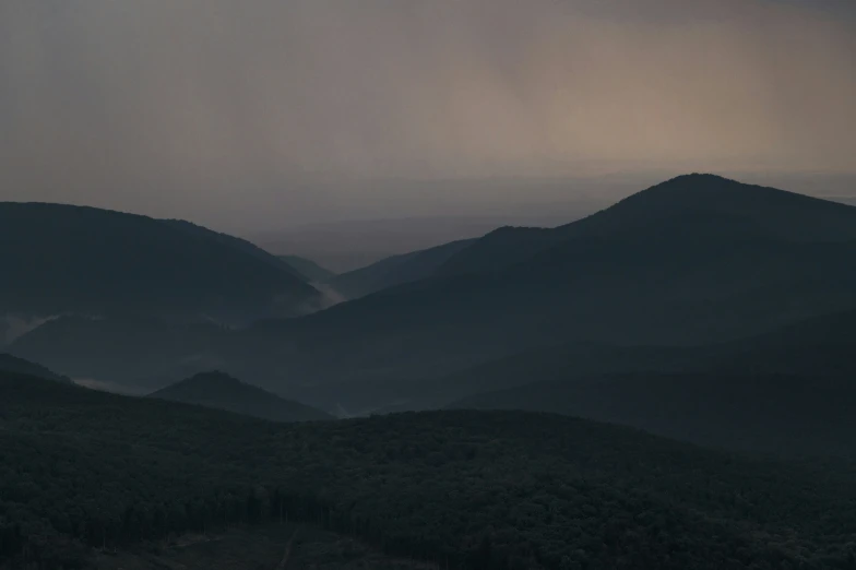 a foggy mountain range is shown in dark colors