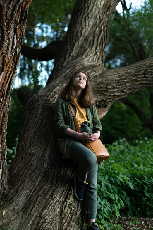 a woman is sitting on a tree with a purse in her hand