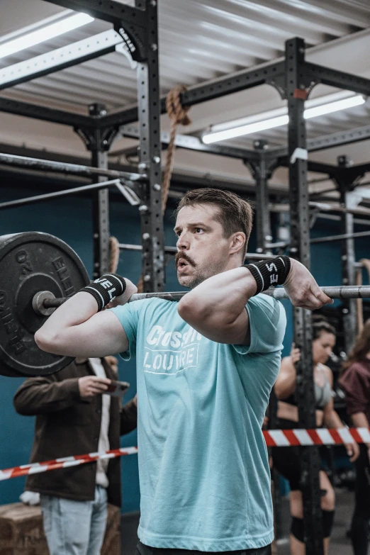 a man squatting while holding onto one arm in a gym