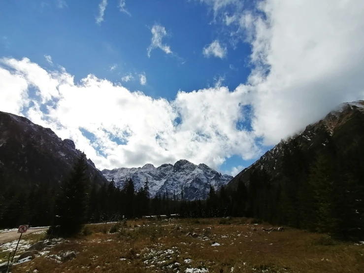 mountains with white clouds above them and a path