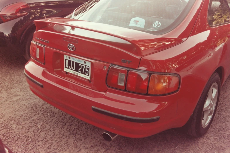 a red toyota car sits in a parking lot