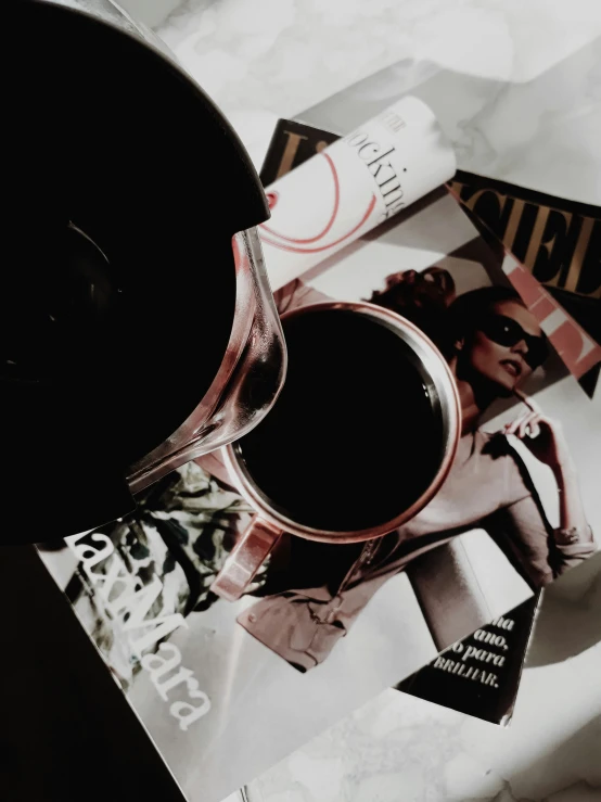 a cup of coffee sitting on top of a pile of magazines