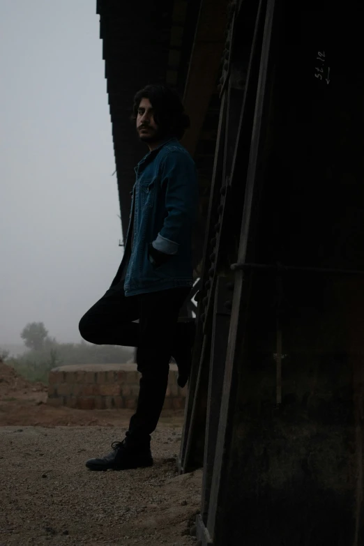 man standing against a wooden fence in dark country