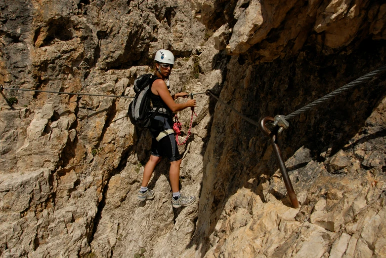 a man with a backpack on his back is rapping off a cliff