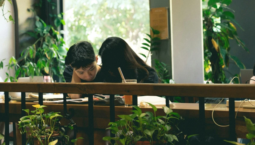 two people sitting at a table with a laptop