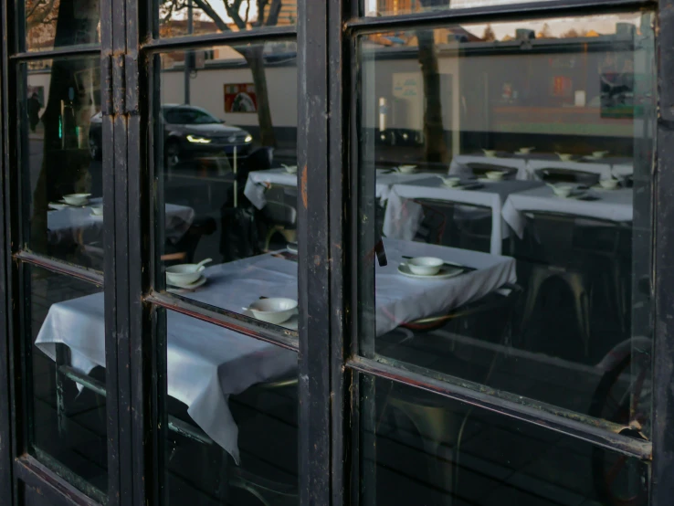 several tables set in front of the windows of a restaurant