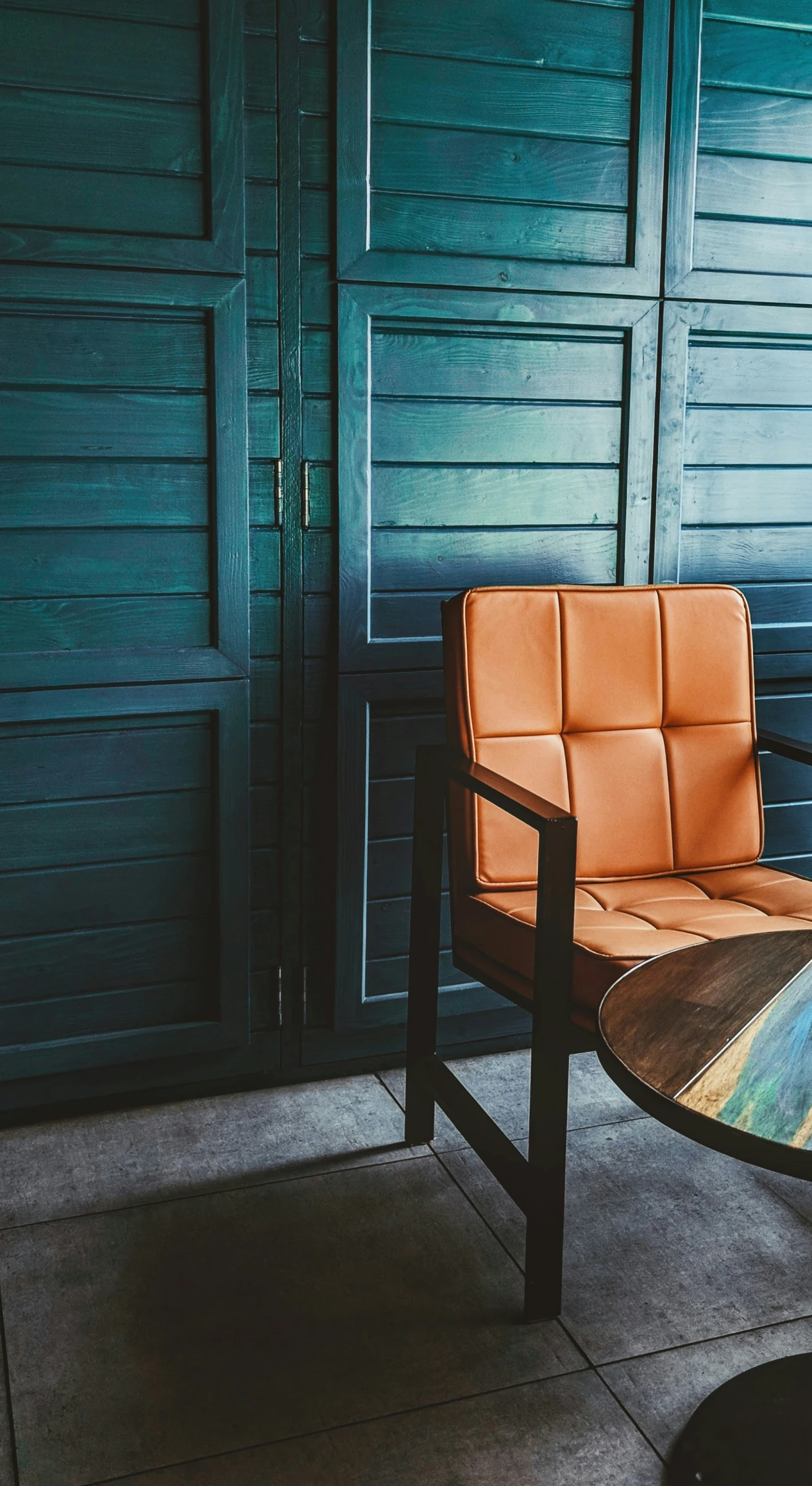 a brown leather chair sitting outside near a black door