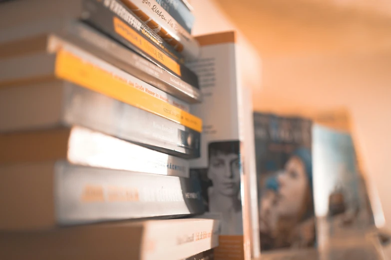 a stack of books sitting on top of a book shelf