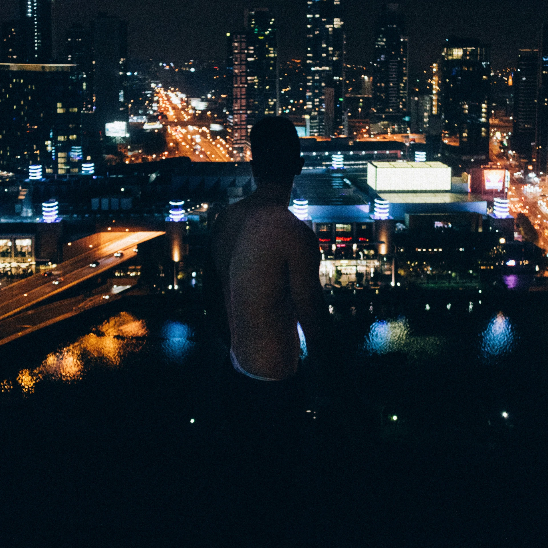 a man in a white shirt staring at the city lights