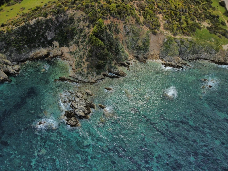 an aerial view of green hills, blue water and a sandy beach