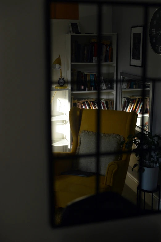 a chair sits in a corner with a book shelf and books on the far wall