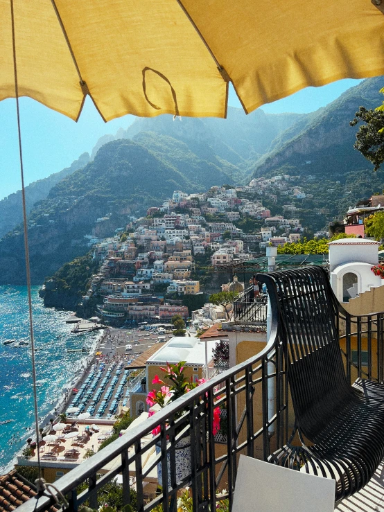 an open umbrella is over two chairs on a balcony overlooking the ocean